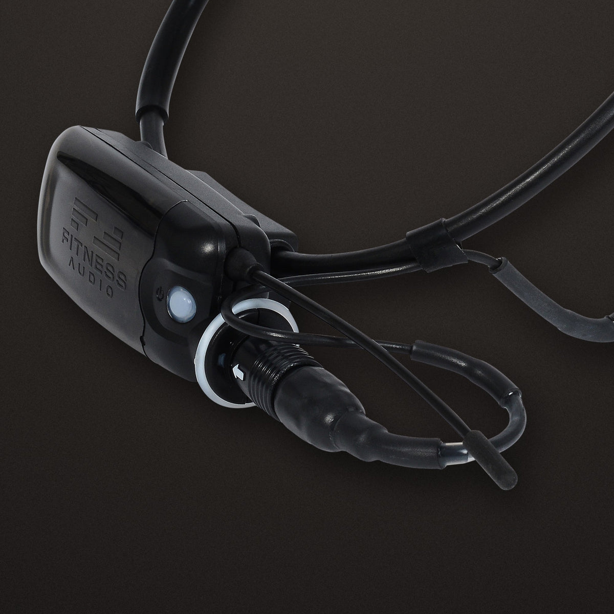 MTU8 mini transmitter mounted on the frame of an Aeromic headset, showing the embossed Fitness Audio logo, power button and headset connector, on a dark background