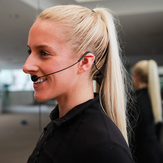 Fitness instructor wearing a black Fitness Audio FM41 headset, smiling from a side profile view. 